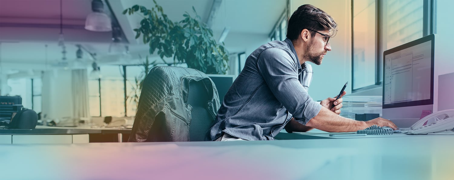 man_looking_computer_holding_pen